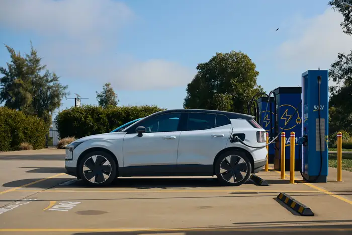 A white electric crossover plugged in at a public charger